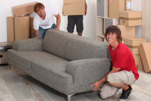 Movers carrying boxes through a London apartment building corridor